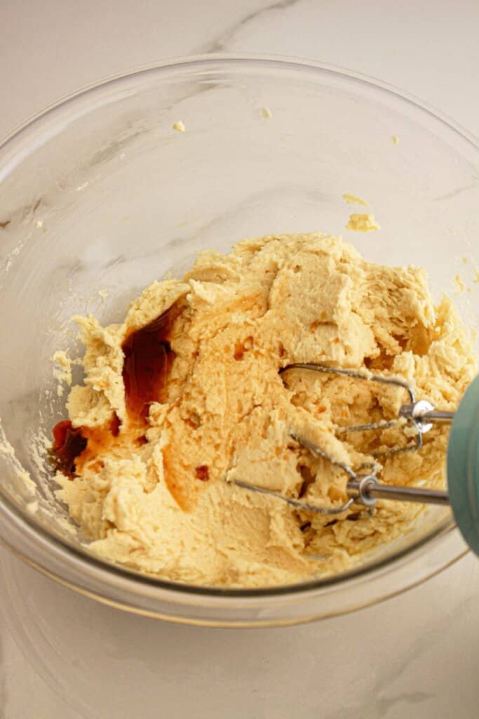 Vanilla being added to dough in a glass mixing bowl.