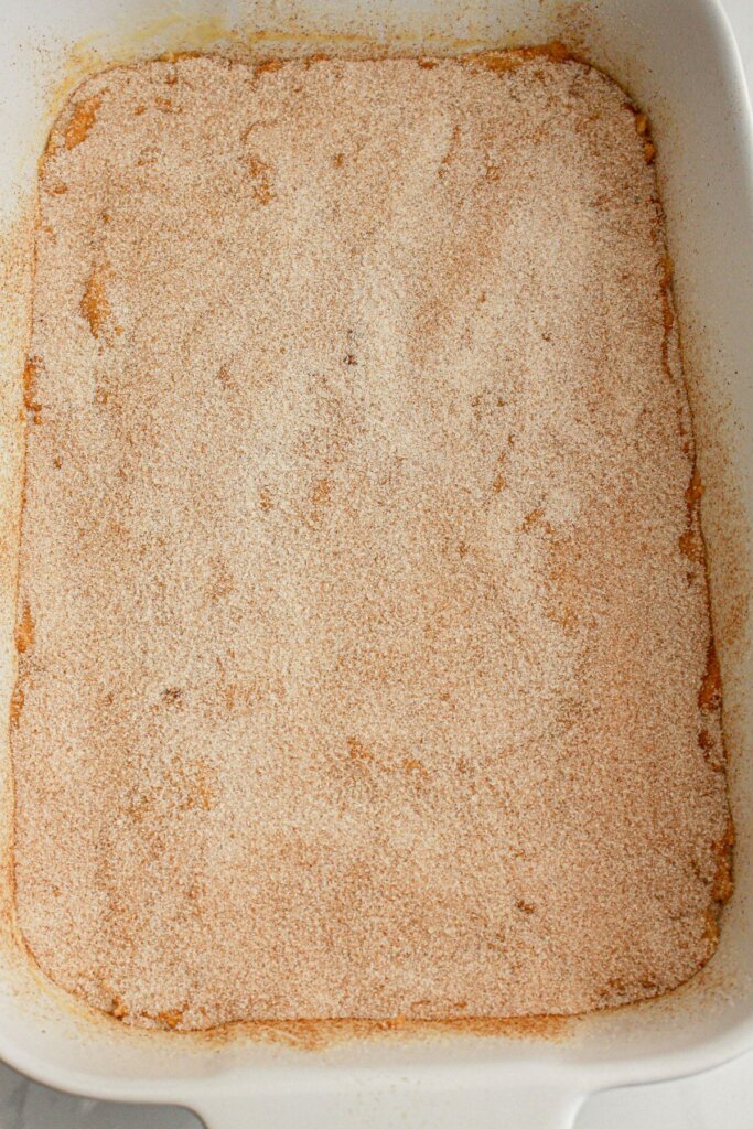 Cinnamon sugar is being sprinkled on the dessert.