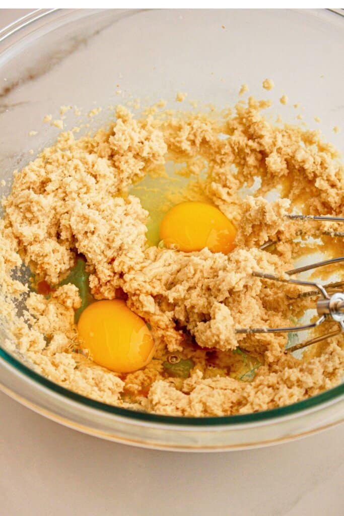Eggs being added to butter in a mixing bowl.