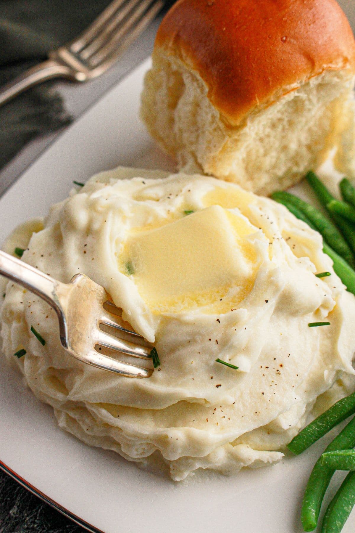White bowl full of cream cheese mashed potatoes.