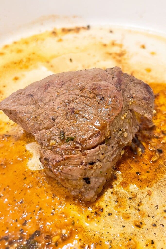 Steak being cooked in a skillet.