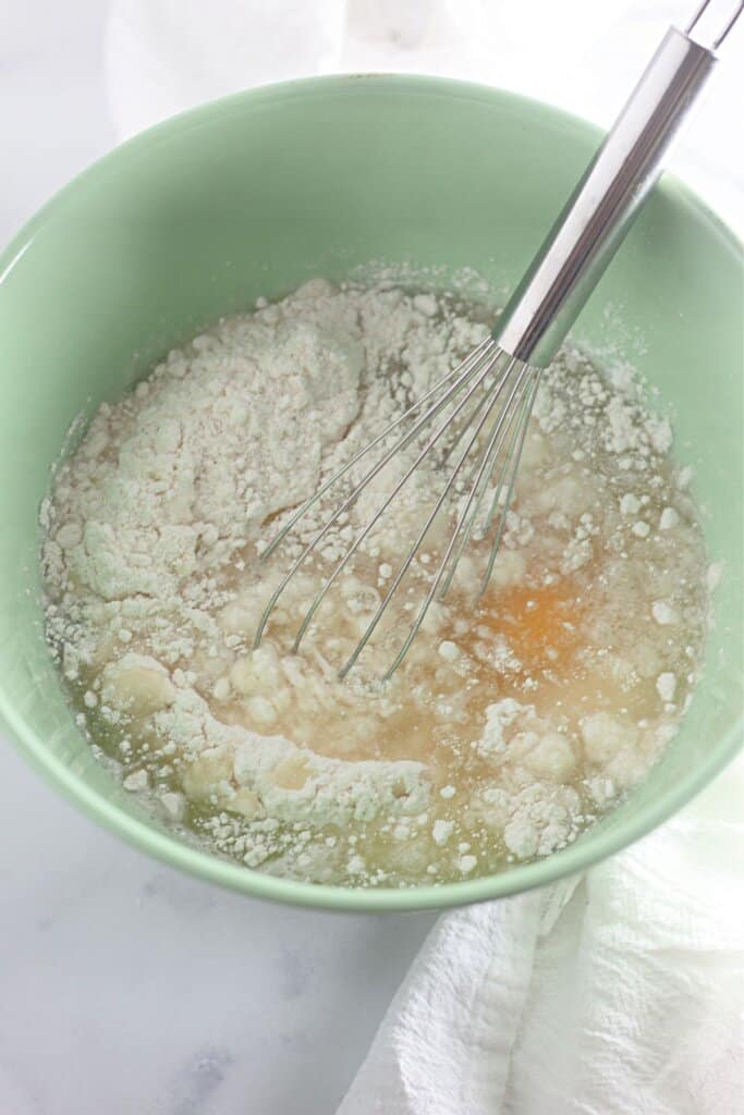 Batter being mixed in a green bowl.