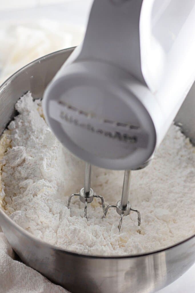 Butter and powdered sugar are being mixed with a hand mixer.