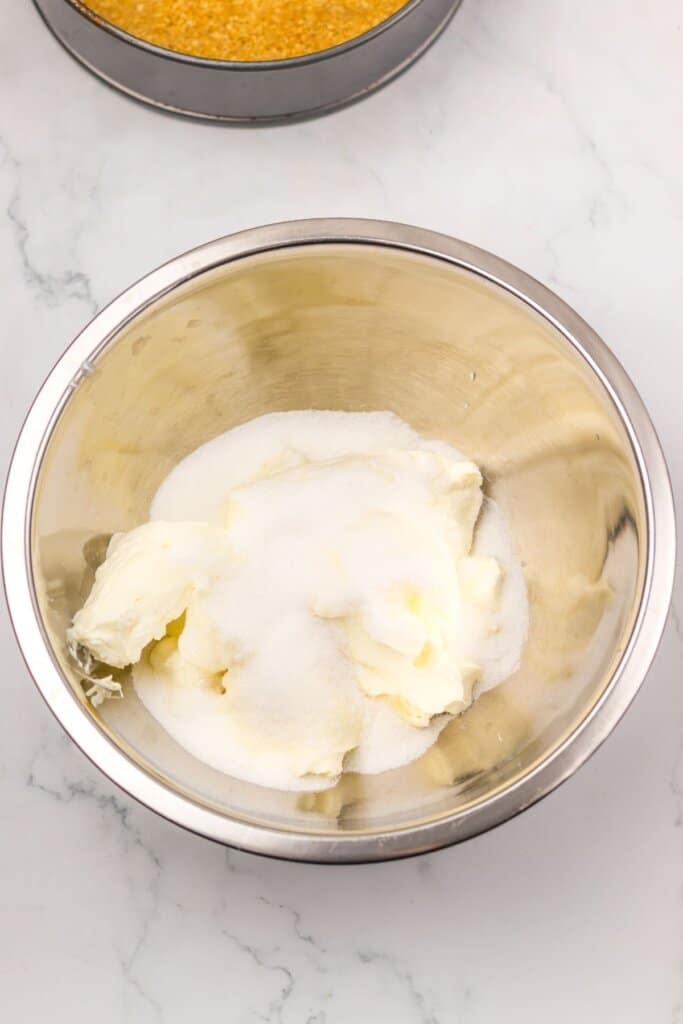 Cream cheese and sugar being mixed in a bowl.