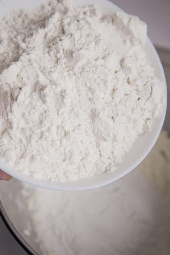 Flour being added to dough in a mixing bowl.
