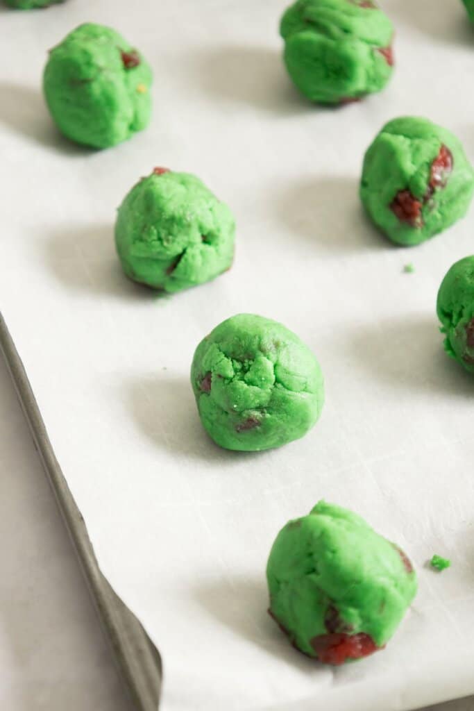 Dough balls on a parchment lined baking sheet.