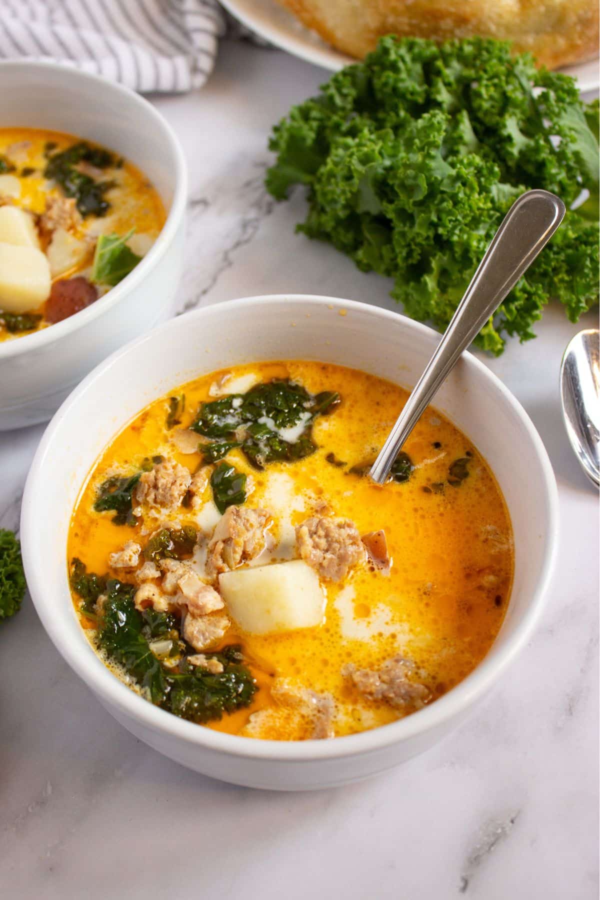 White bowl full of sausage potato and kale soup.