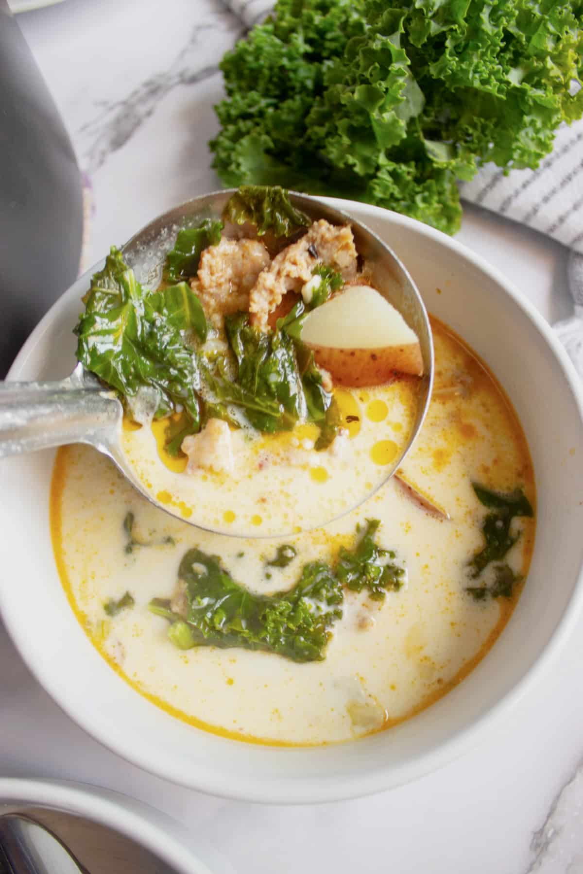 White bowl full of sausage potato and kale soup.