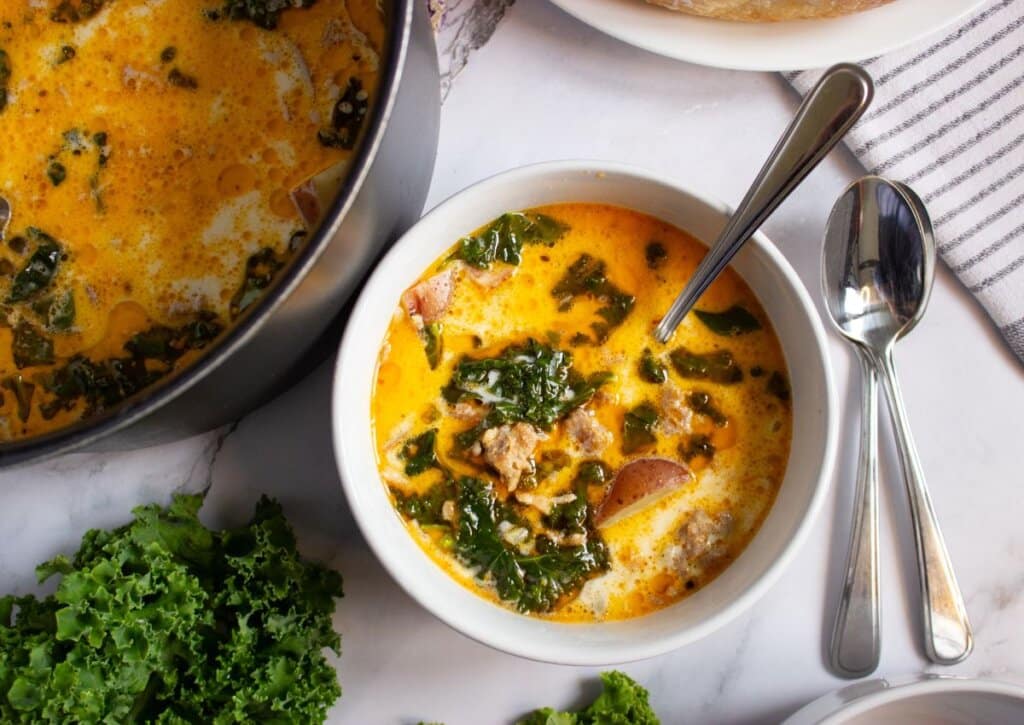 White bowl full of sausage potato and kale soup.