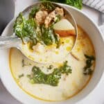 White bowl full of sausage potato and kale soup.