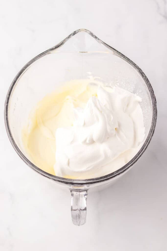 Cream cheese and whipped topping being mixed in a glass bowl.