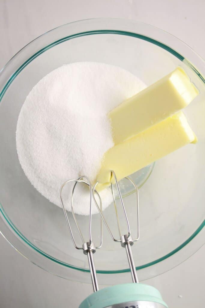 Butter and sugar being mixed in a glass bowl.