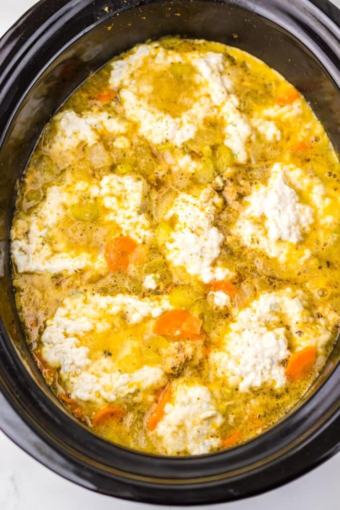 Dough being added to a crock pot.