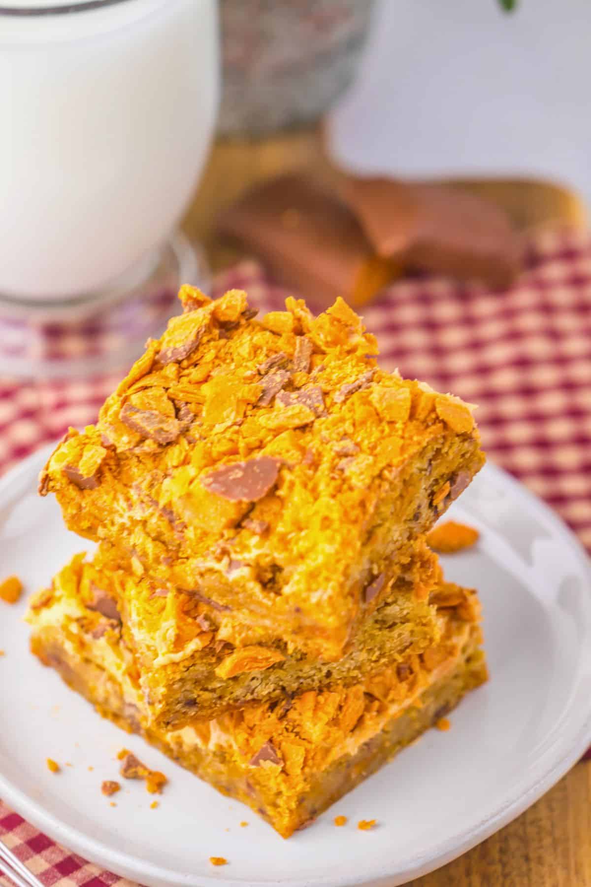 Three butterfinger cookie bars on a plate.