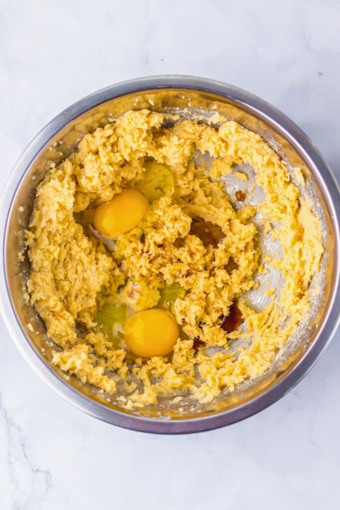 Eggs and vanilla extract being mixed in a metal mixing bowl.