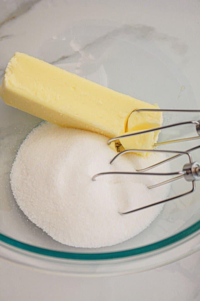 Butter and sugar being mixed in a glass bowl.
