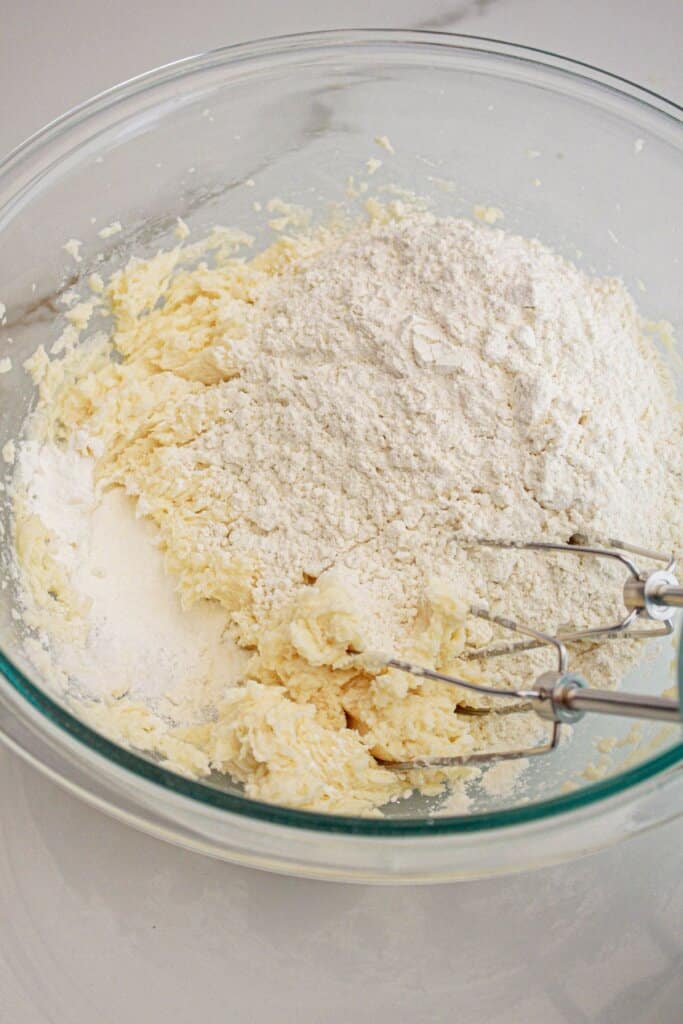 Dry ingredients being added to a glass bowl.