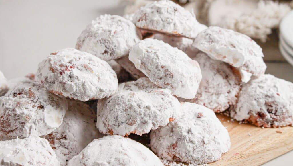 Cherry snowball cookies on a wooden cutting board.