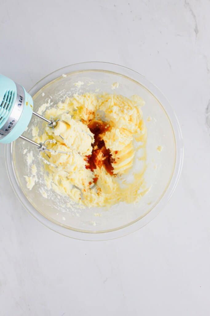 Vanilla extract being added to dough in a glass bowl.