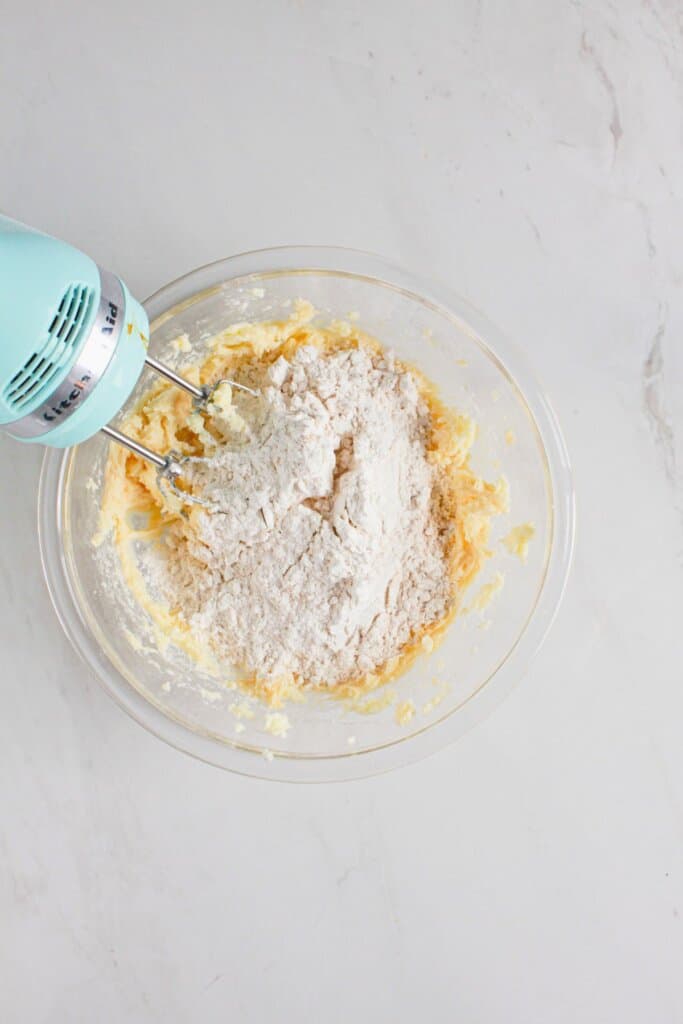 Flour being added to dough in a glass bowl.