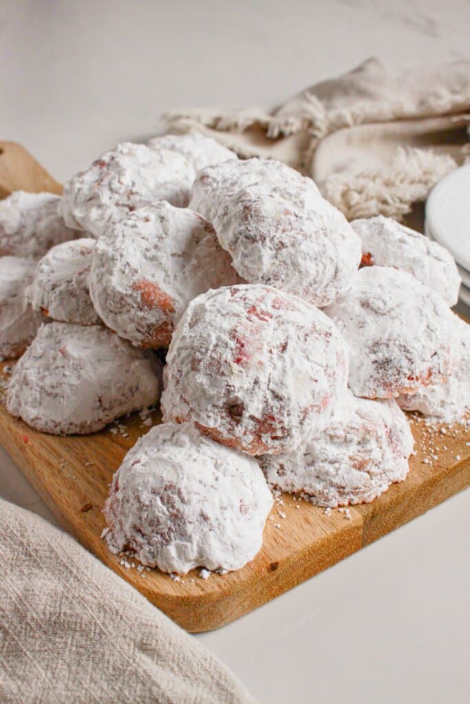 Cherry snowball cookies on a wooden cutting board.