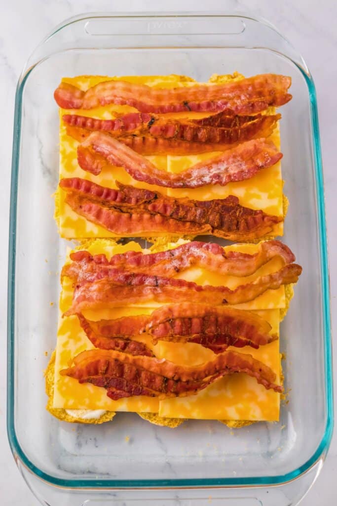 Bacon being laid on top of sandwiches.