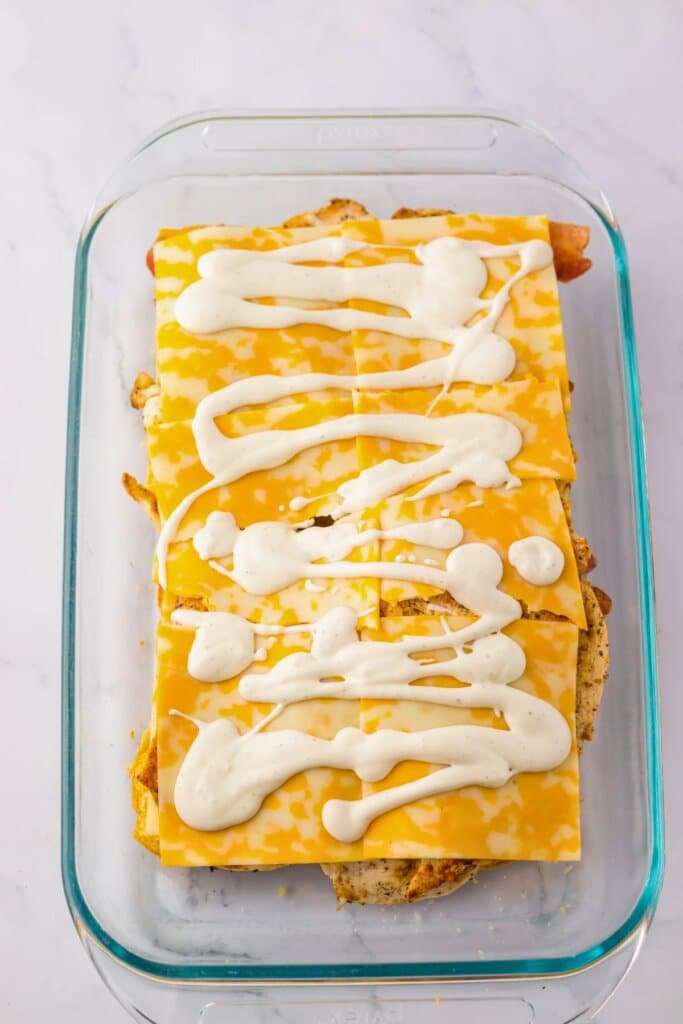 Ranch being drizzled on top of sandwiches.