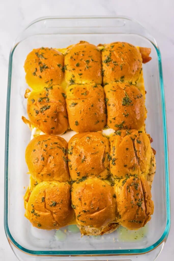 Melted butter being brushed on top of rolls.