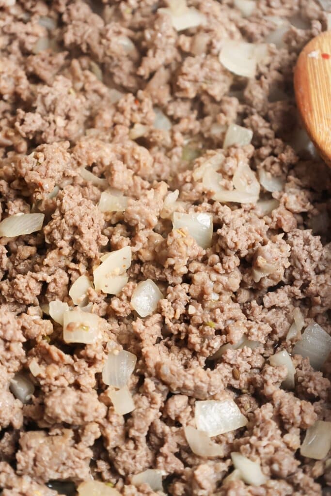 Ground beef and onions being cooked in a skillet.