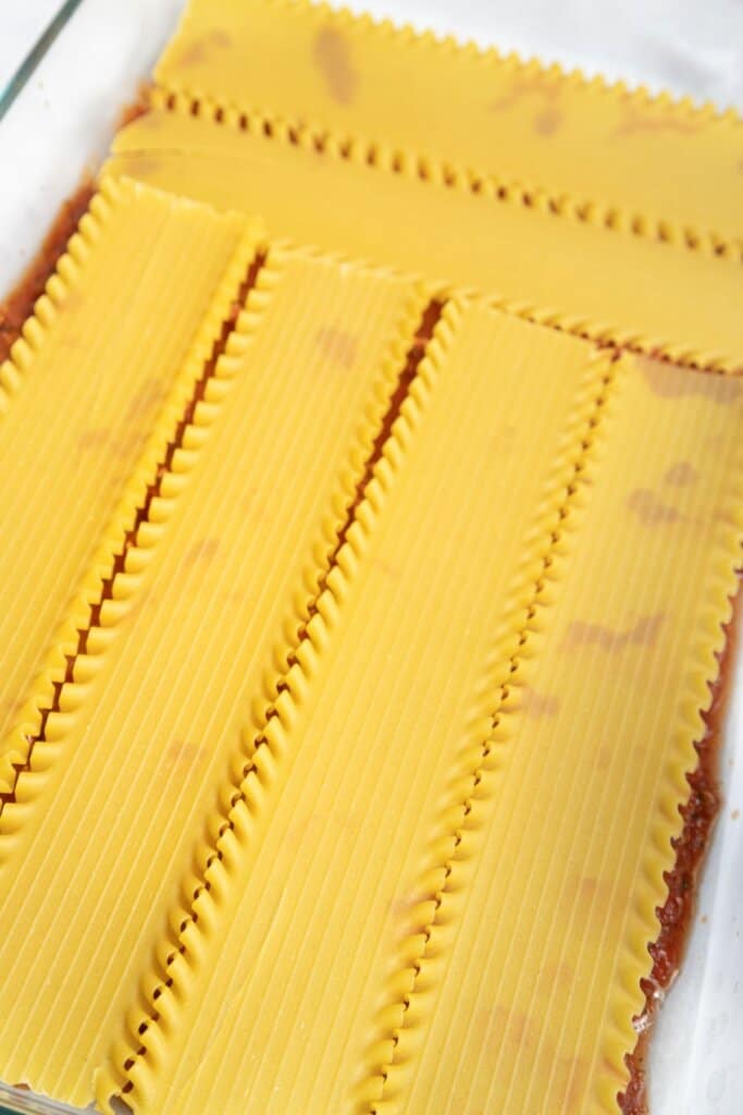 Noodles being layered in a baking dish.
