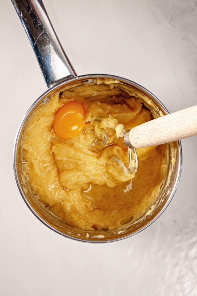 Eggs being added to batter in a saucepan.