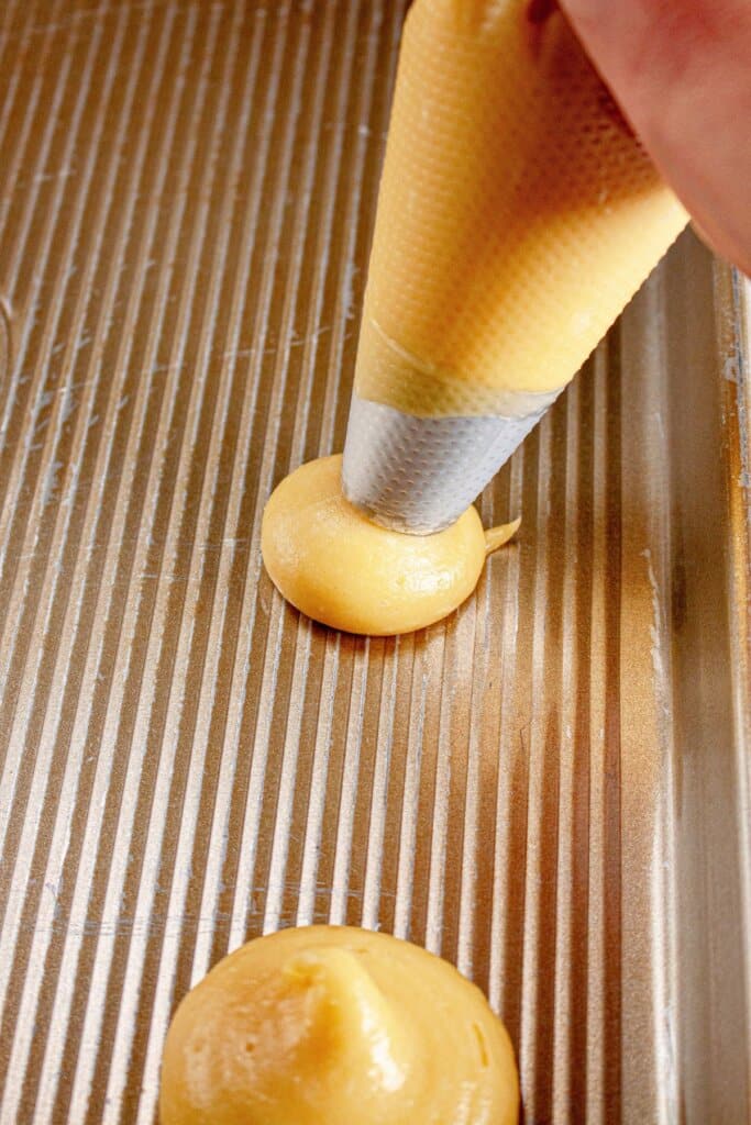 Dough being piped onto a baking sheet.