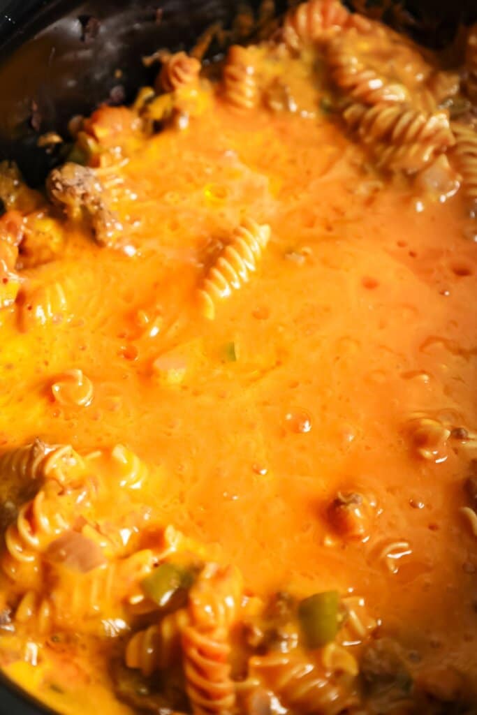 Cheese on top of pasta in a slow cooker.