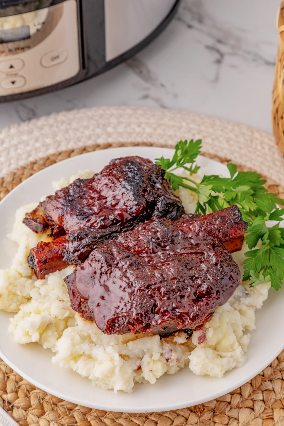 BBQ ribs on top of a bed of mashed potatoes on a plate.