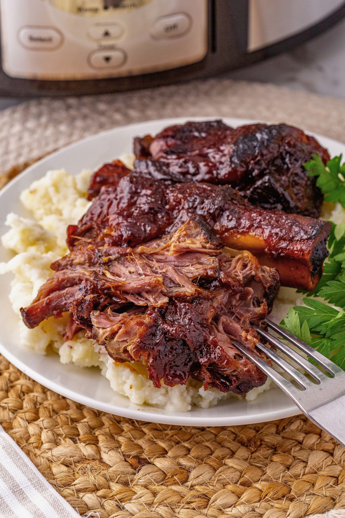 BBQ ribs on top of a bed of mashed potatoes on a plate.