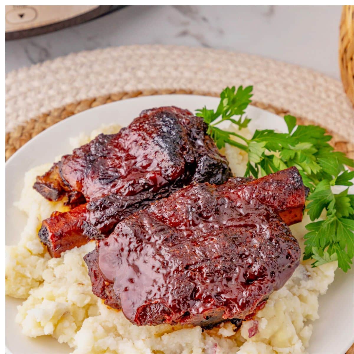 BBQ ribs on top of a bed of mashed potatoes on a plate.