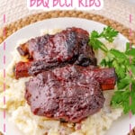 BBQ ribs on top of a bed of mashed potatoes on a plate.