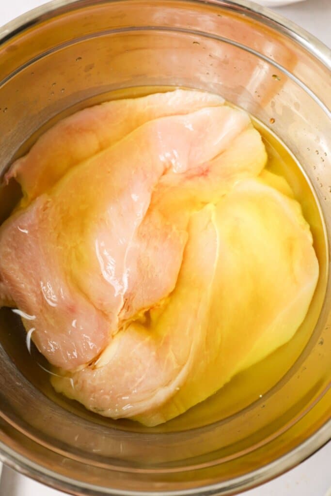 Raw meat marinading in a bowl of pickle juice.