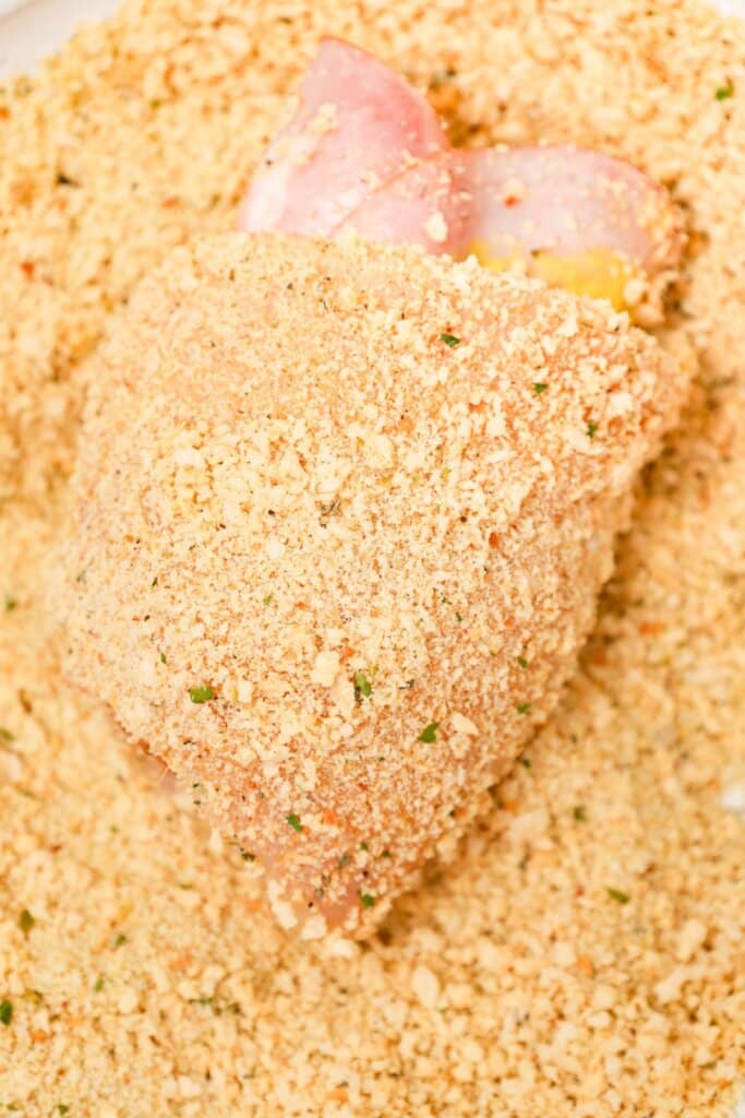 Raw meat being rolled in bread crumbs.