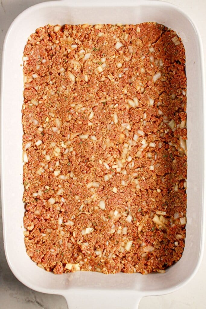 Ground beef mixture pressed into a baking sheet.