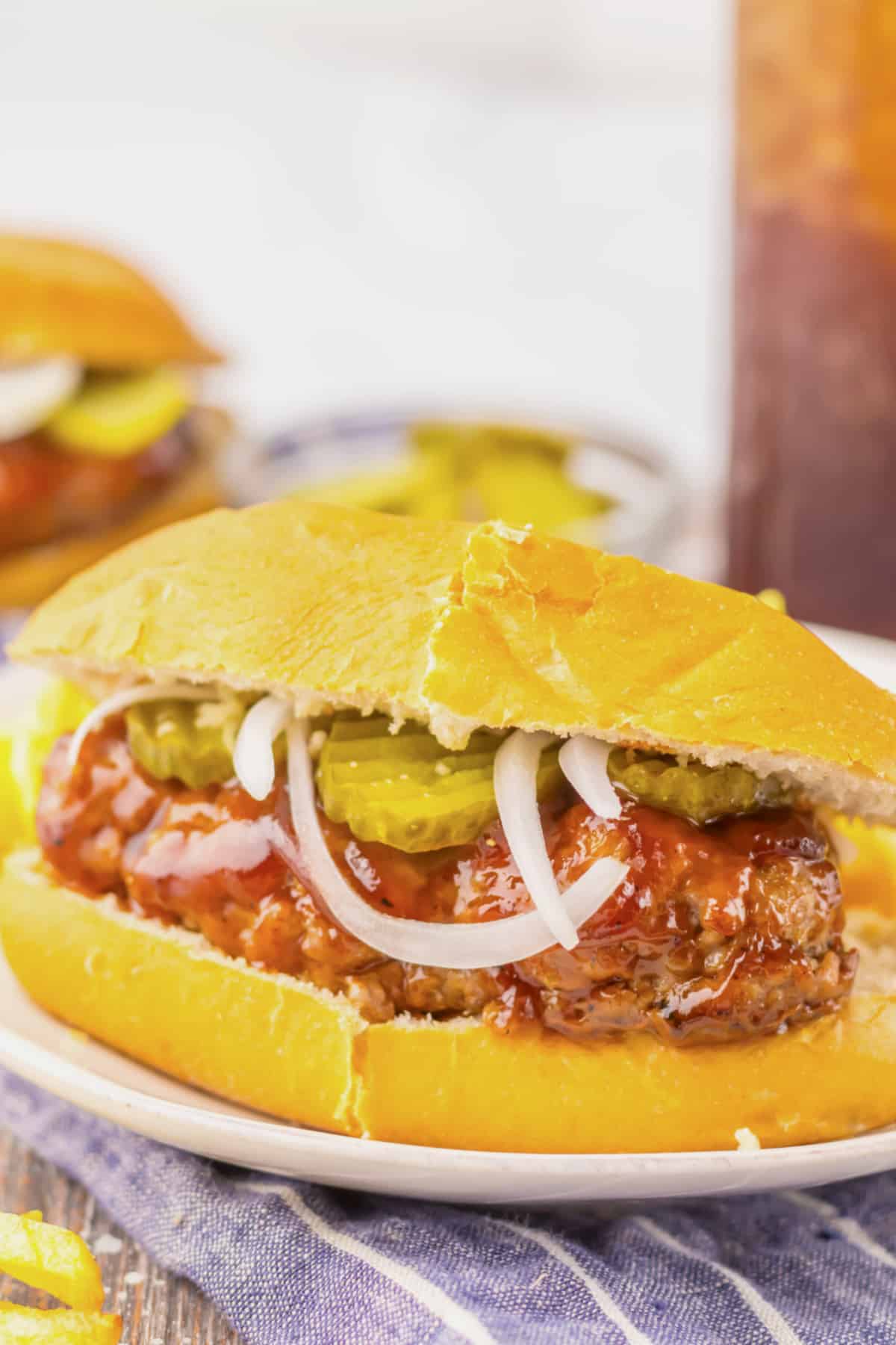 Mcrib sandwich on a plate with some fries.