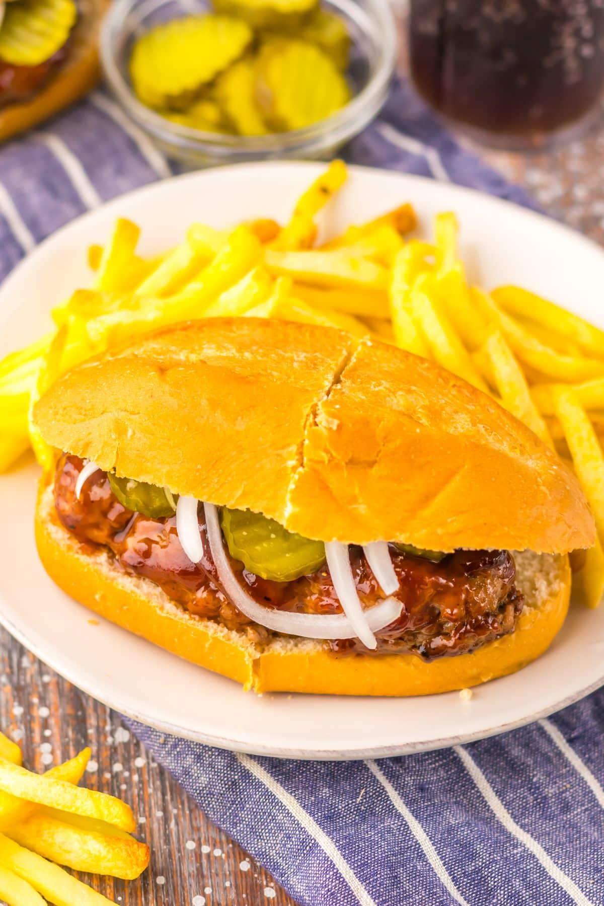 Mcrib sandwich on a plate with some fries.