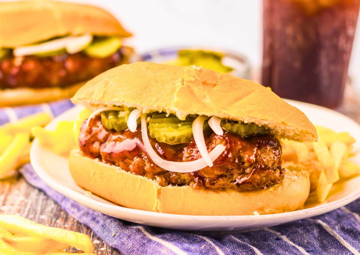 Mcrib sandwich on a plate with some fries.