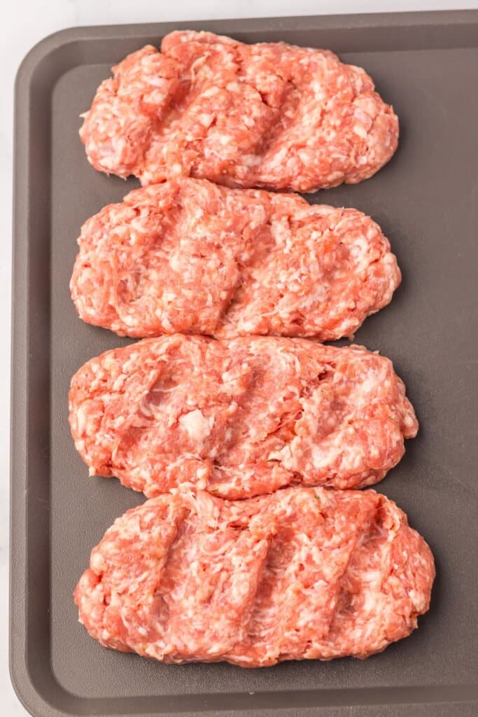 Pork patties on a baking sheet.