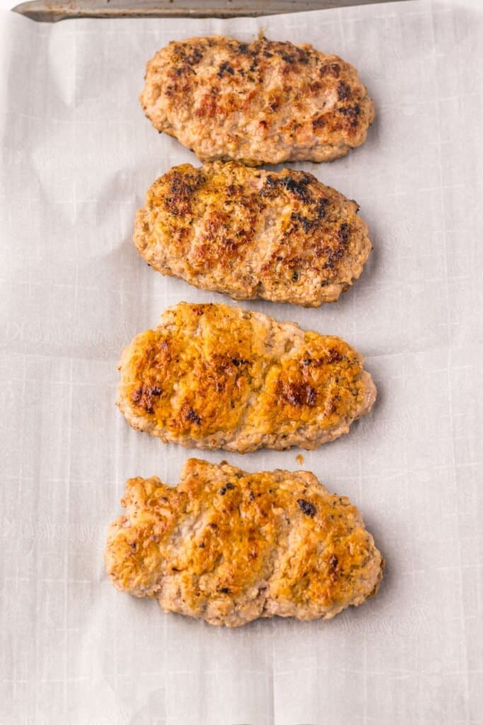 Cooked pork patties on a baking sheet.