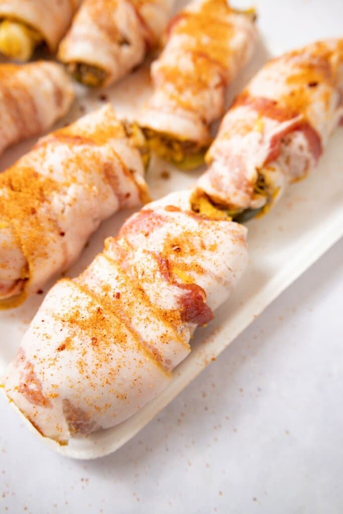 Bacon wrapped poppers on a tray.