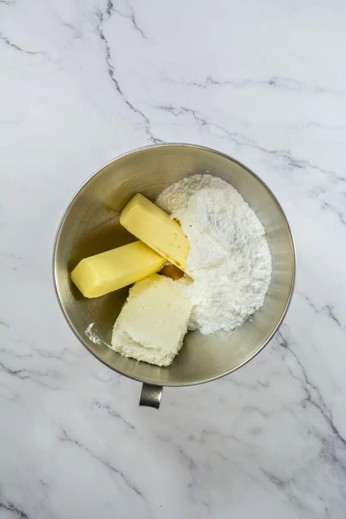 Butter cream cheese and powdered sugar being mixed in a bowl.
