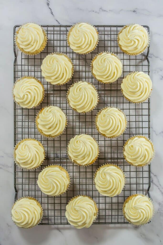 Desserts being decorated on a wire rack.