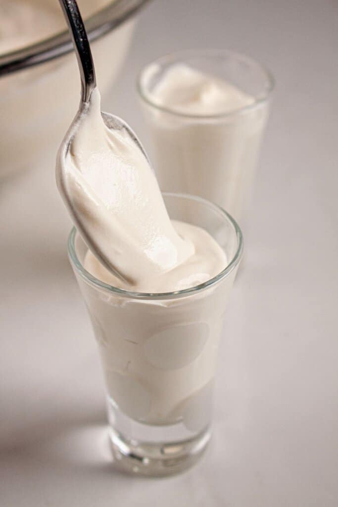 Dessert being spooned into shot glasses.