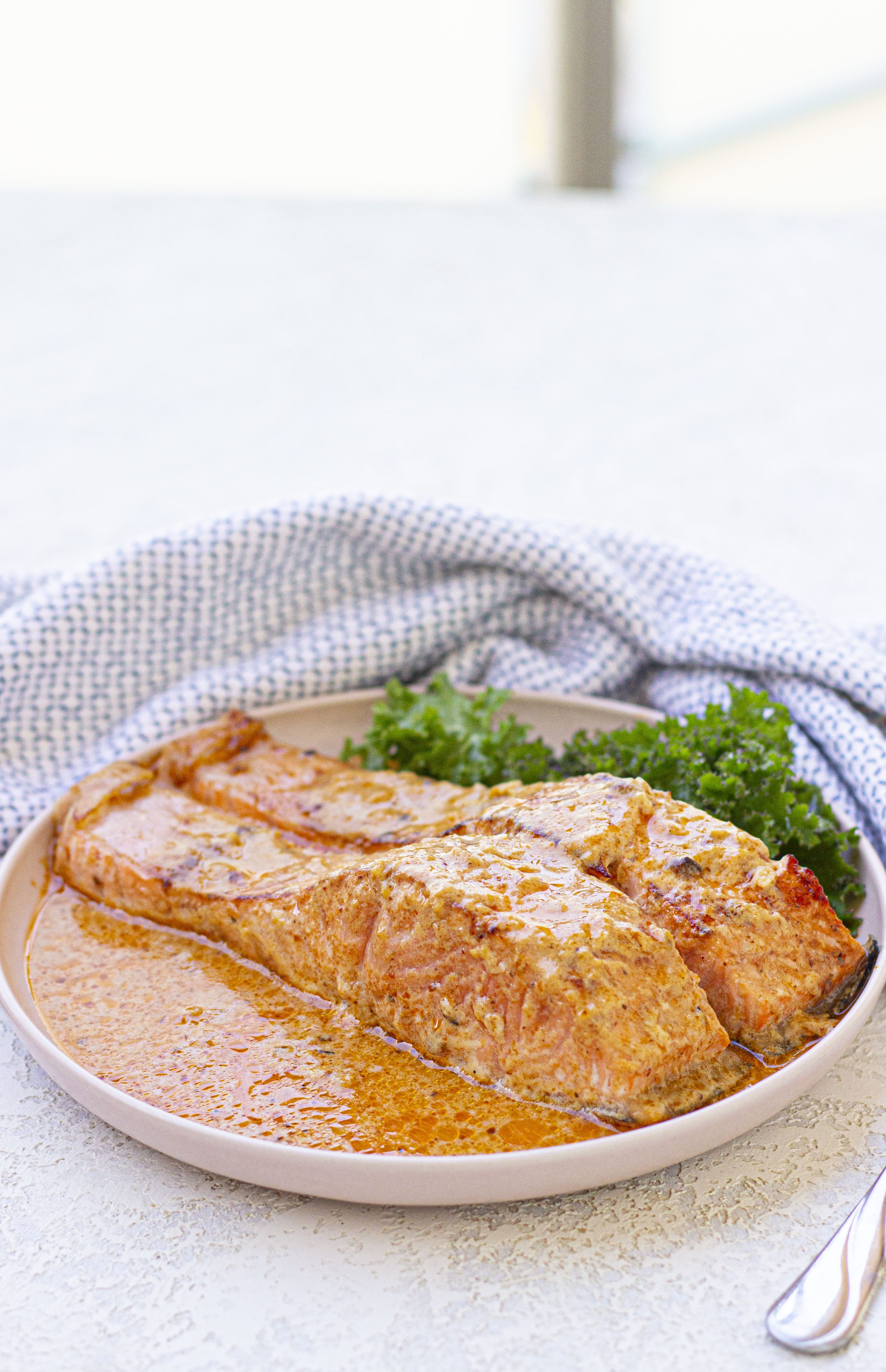 Two salmon filets in cream sauce on a plate.